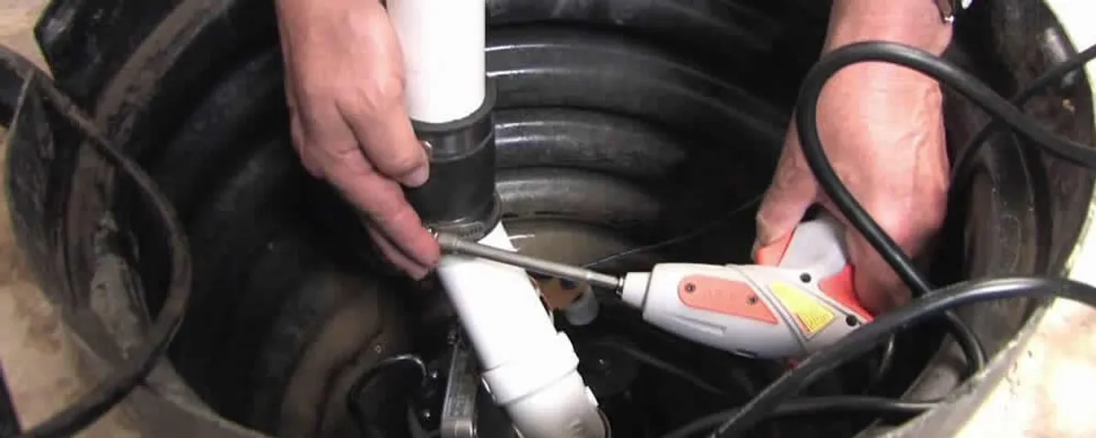 Sump pump installation technician connecting PVC discharge piping in Oakland, CA